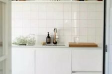 41 a Scandinavian kitchen in white, with a stacked square tile backsplash and an open shelf over the cabinets