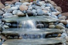 41 a natural looking waterfall done with large rocks and with pebbles around will bring a fresh feel to your front yard