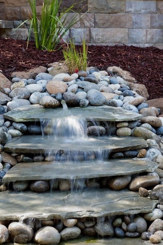 a natural looking waterfall done with large rocks and with pebbles around will bring a fresh feel to your front yard