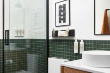 43 a modern bathroom with white walls and dark green square tiles, a stained vanity, a shower with black framing and pendant lamps