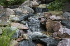 44 a pretty all-natural waterfall composed of large and small rocks, with greenery and pink blooms is a cool idea for a garden