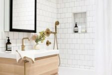 46 a neutral bathroom clad with white square tiles and hexagon ones, a tub clad with tiles, a timber vanity and brass fixtures
