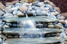 46 a rustic backyard waterfall composed of pebbles and large flat rocks is a cool and easy to DIY solution for your garden