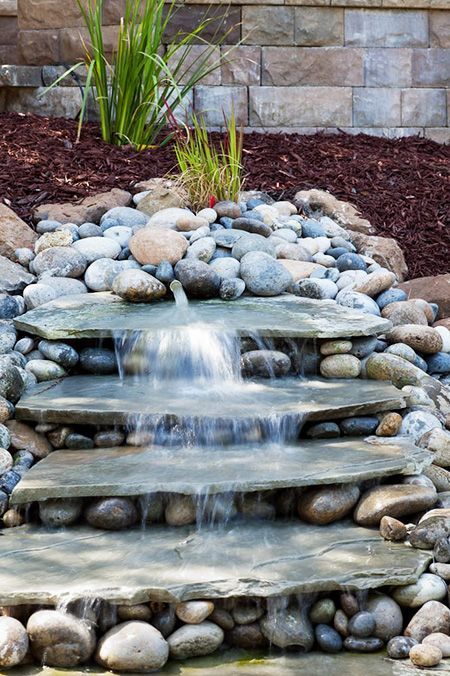 a rustic backyard waterfall composed of pebbles and large flat rocks is a cool and easy to DIY solution for your garden