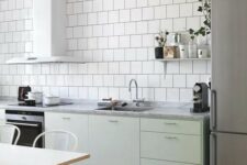 47 a Scandinavian kitchen with white square tiles, mint green cabinets, stainless steel appliances and white chairs and a table