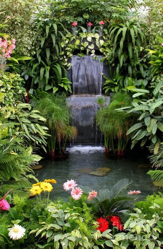 a super lush garden waterfall surrounded with lush greenery and bright blooms will be a gorgeous accent feature in the space