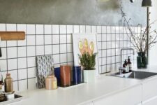 53 a white Scandinavian kitchen with a white tile backsplash with black grout, grey walls and grey sconces