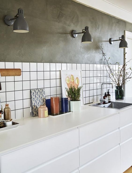 a white Scandinavian kitchen with a white tile backsplash with black grout, grey walls and grey sconces