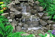 54 an Alpine-style waterfall made of rocks, with greenery and bright blooms around is a cool and bright way to add interest to your garden
