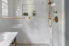 55 a refined bathroom with white square and printed tiles, white marble, elegant brass fixtures and a window