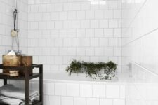 56 a simple white bathroom with white square tiles and a grey marble tile floor, a black shelving unit, some greenery and decor