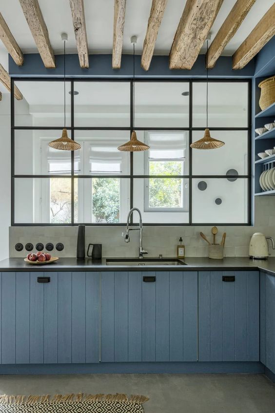 a beautiful ocean blue kitchen with shiplap cabinets, a grey concrete backsplash and open cabinets, wooden beams on the ceiling