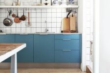 a blue Scandi kitchen with only lower cabinets, white square tiles, an open shelf and a large kitchen island