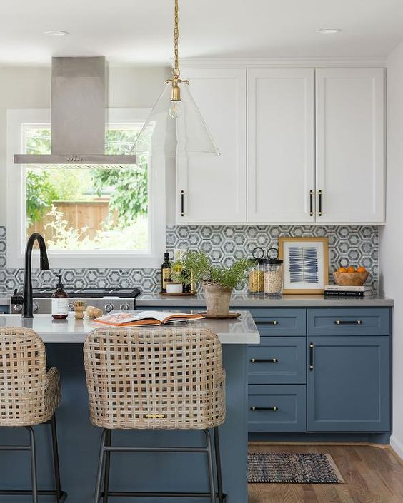 a blue and white kitchen with a hex tile backsplash, white countertops, woven stools and a cool pendant lamp