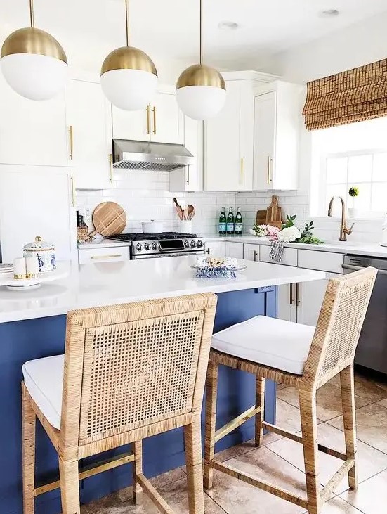 a bold coastal kitchen with white cabinets, a navy kitchen island with a white countertop, rattan chairs, woven shades and open shelves