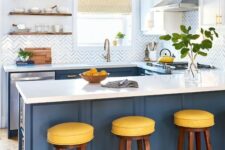 a bright kitchen with navy cabinets, white countertops and a chevron backsplash plus touches of brass and gold