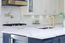 a bright kitchen with white cabinets, a blue kitchen island and hood and lots of gold to make the space exquisite
