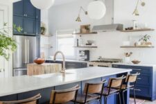 a bright modern kitchen with bold blue lower cabinets and a kitchen island, white countertops and a backsplash