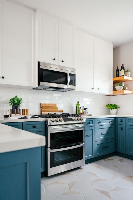 a cheerful kitchen with white upper and blue lower cabinets, a white tile backsplash and countertops, open shelves