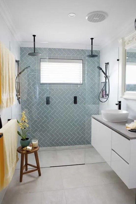 a chic tiny bathroom with light blue tiles, a floating white vanity with a cocnrete countertop, black fixtures and bold linens