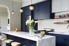 a chic two tone kitchen in white and navy, with a white marble countertop and tile backsplash plus wooden stools