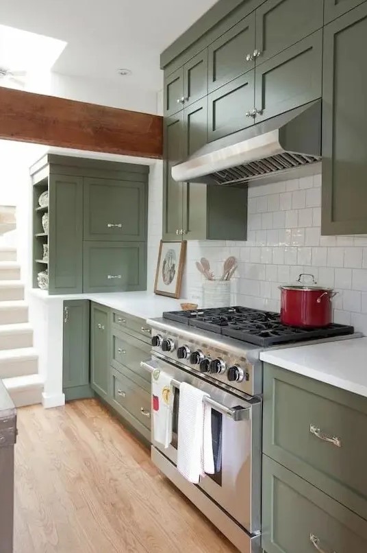 a classic sage green kitchen with shaker cabinets, a white square tile backsplash, white countertops and stainless steel appliances