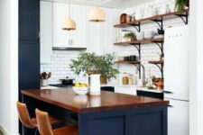 a contrasting kitchen with navy lower and white upper cabinets, a white subway tile backsplash, tall stools and pendant lamps