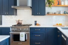 a contrasting kitchen with navy shaker cabinets, a white tile backsplash and countertops, open shelves and black sconces