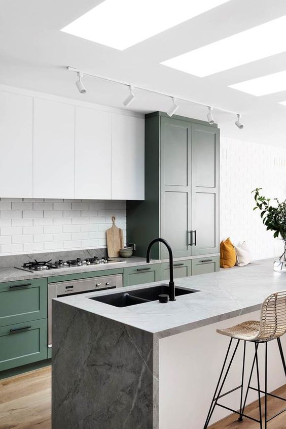 a cool kitchen with white and green cabinets, a grey stone kitchen island, a white tile backsplash and a black faucet