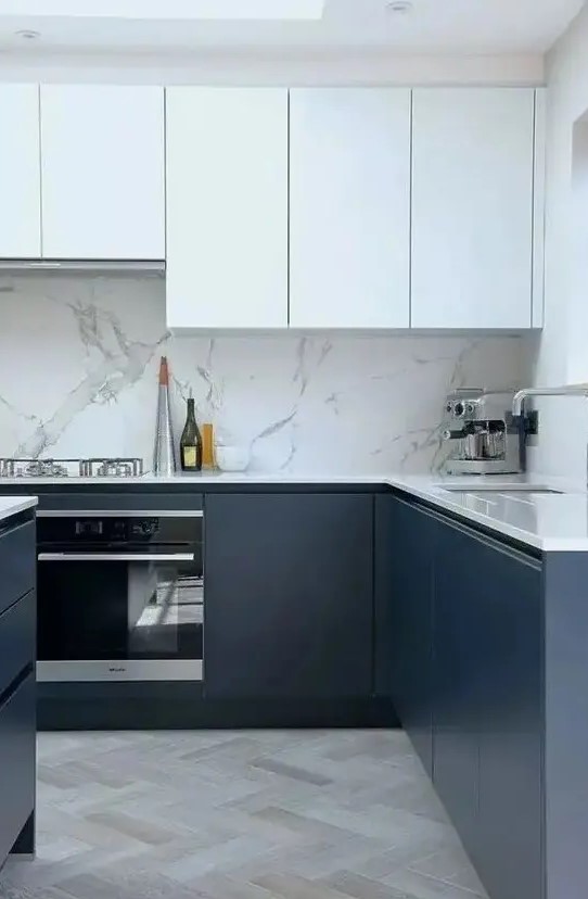 a fab contemporary kitchen with sleek white and navy cabinets, a white stone backsplash and countertops and a skylight
