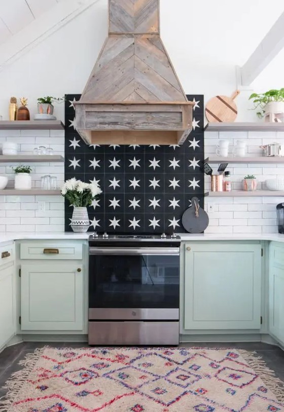a farmhouse kitchen with mint lower cabinets, open shelves, a white tile backsplash, a reclaimed wood hood