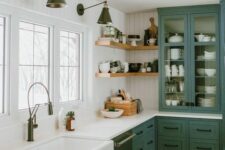 a farmhouse kitchen with white shiplap walls, green cabinets, white countertops and vintage sconces is chic
