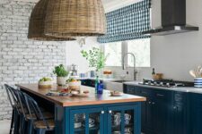 a lovely kitchen with deep blue cabinets, a storage kitchen island, blue plaid shades, woven pendant lamps