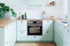 a lovely mint blue Scandinavian kitchen with plywood cabinets, butcherblock countertops, a square tile backsplash and pendant bulbs