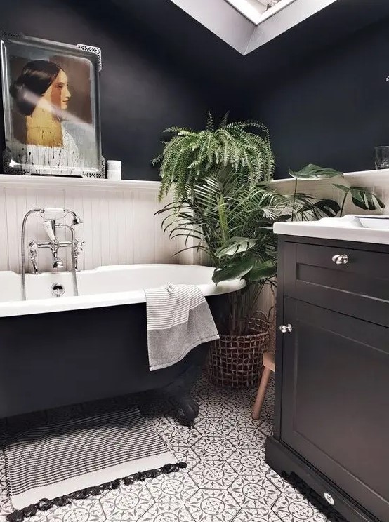 a lovely modern bathroom with black walls, white planks, a black vanity, a black tub, patterned tiles, a skylight and an artwork