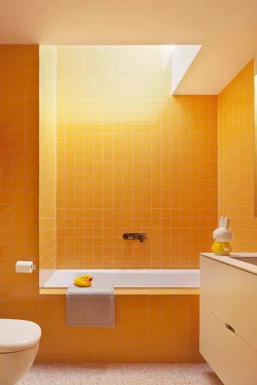 a minimalist bathroom with sunny yellow square tiles all over the space, a floating vanity with a sink and a skylight that fills the room with natural light