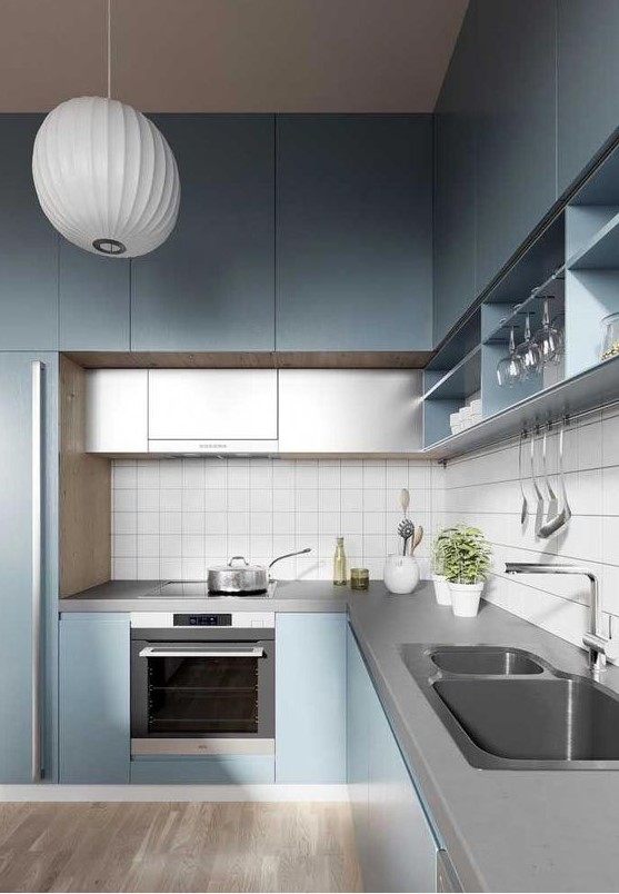 a minimalist light blue kitchen with grey additional cabinets and a concrete countertop plus a white tile backsplash