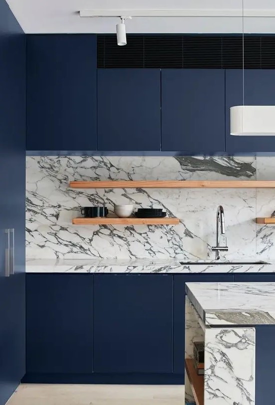 a minimalist navy kitchen with a neutral marble backsplash, open shelves and a chic kitchen island