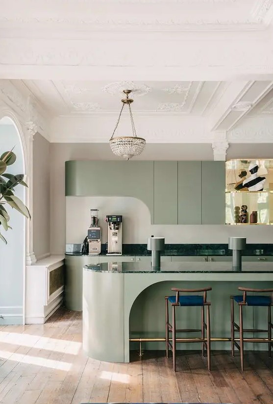 a modern and very refined sage green kitchen with curved cabinetry, a sculptural kitchen island and dark green countertops