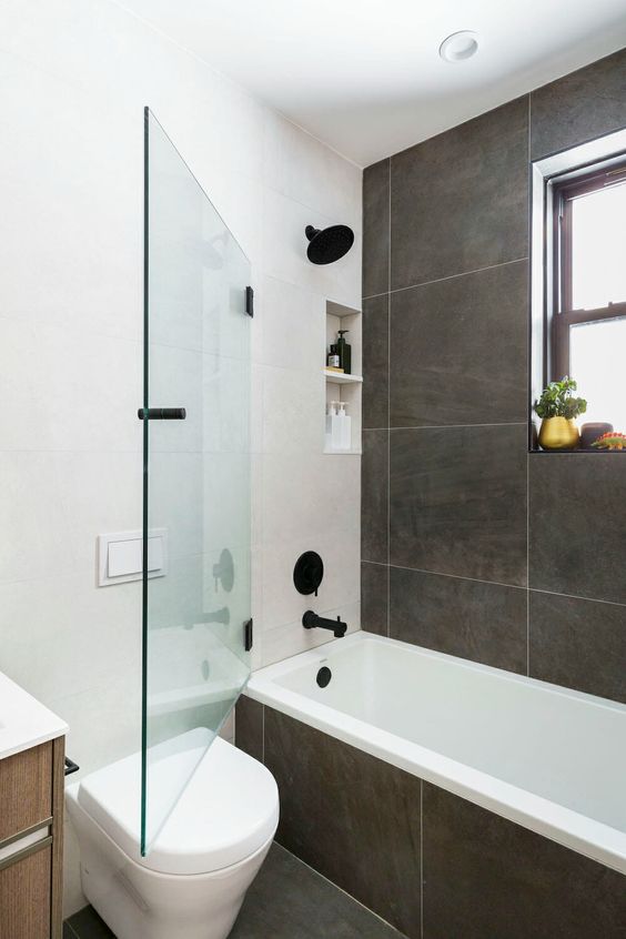 a modern bathroom with grey large format tiles, black fixtures, a timber vanity and a small window