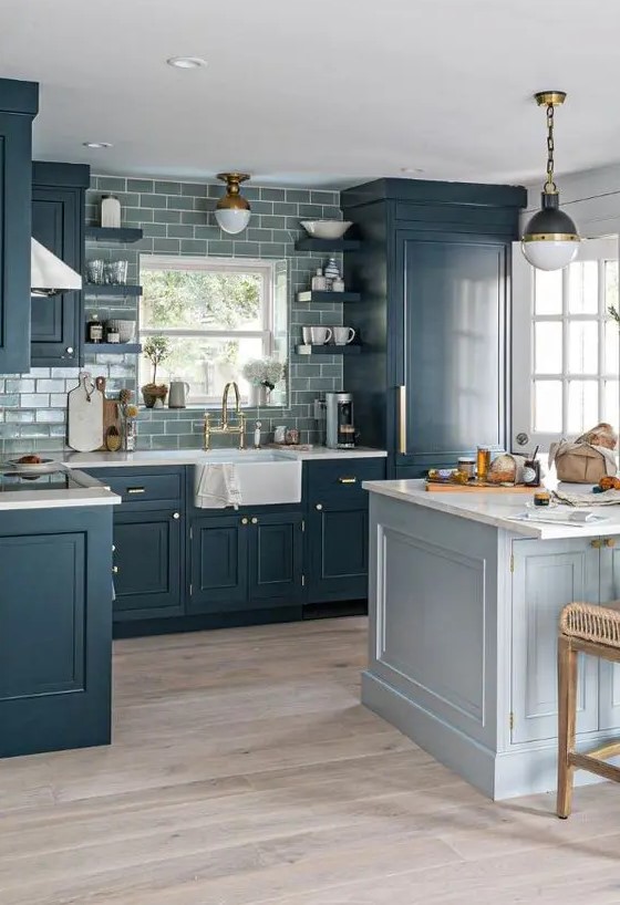 a modern farmhouse kitchen with navy shaker cabients, a grey subway tile backsplash, a pale blue kitchen island, a lamp on chain