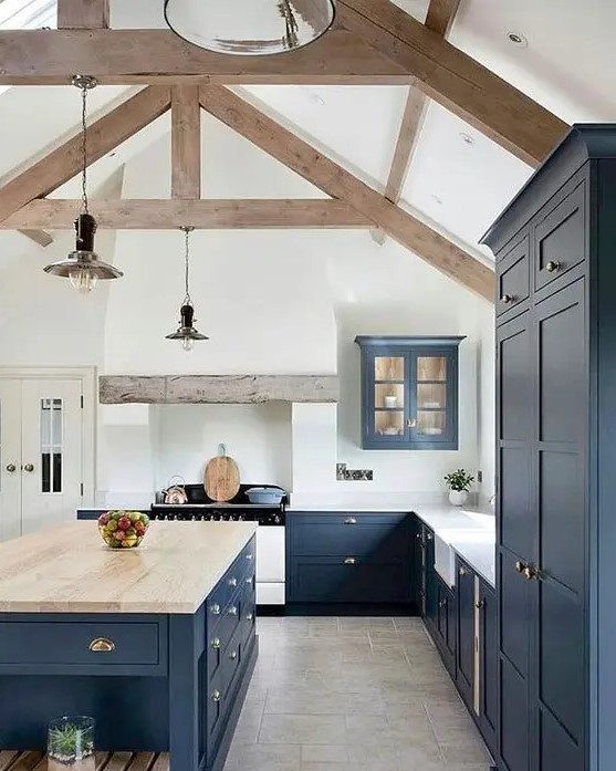 a navy kitchen with a white backsplash, countertops, a large island with a wooden countertop and wooden beams