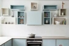a pastel blue Scandinavian kitchen with sleek cabinets, box shelves on the wall and built-in appliances