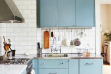 a pastel blue Scandinavian kitchen with white subway tiles, stainless steel appliances and stained touches
