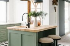 a pretty sage green kitchen with shaker cabinets, a small kitchen island, stone and butcherblock countertops and black pendant lamps