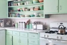 a retro kitchen with flat panel mint cabinets, a large open cabinet, a neutral backsplash and countertops and some retro decor