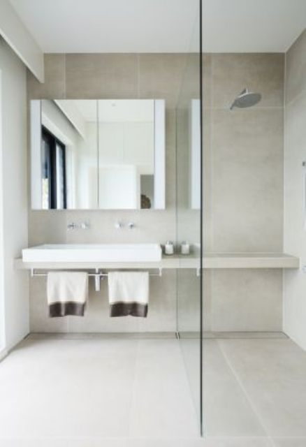 a serene minimalist bathroom with large format tiles, a shower, a built-in vanity, a mirror cabinet is a cool space