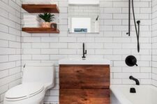 a small and chic modern bathroom with a mosaic floor, a floating wooden vanity, open shelves, a tub and white subway tiles