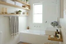a small and serene bathroom with a tub, open shelves, a sink, wicker and wooden touches here and there