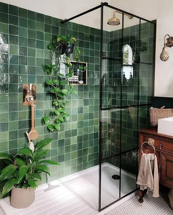 a small bright bathroom with green square tiles, a vintage stained vanity, white appliances and penny tiles on the floor plus potted plants